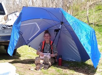 Becca Arnold takes a break for lunch under a large field umbrella at the Lewis Run (LEWI) aquatic site in Virginia.